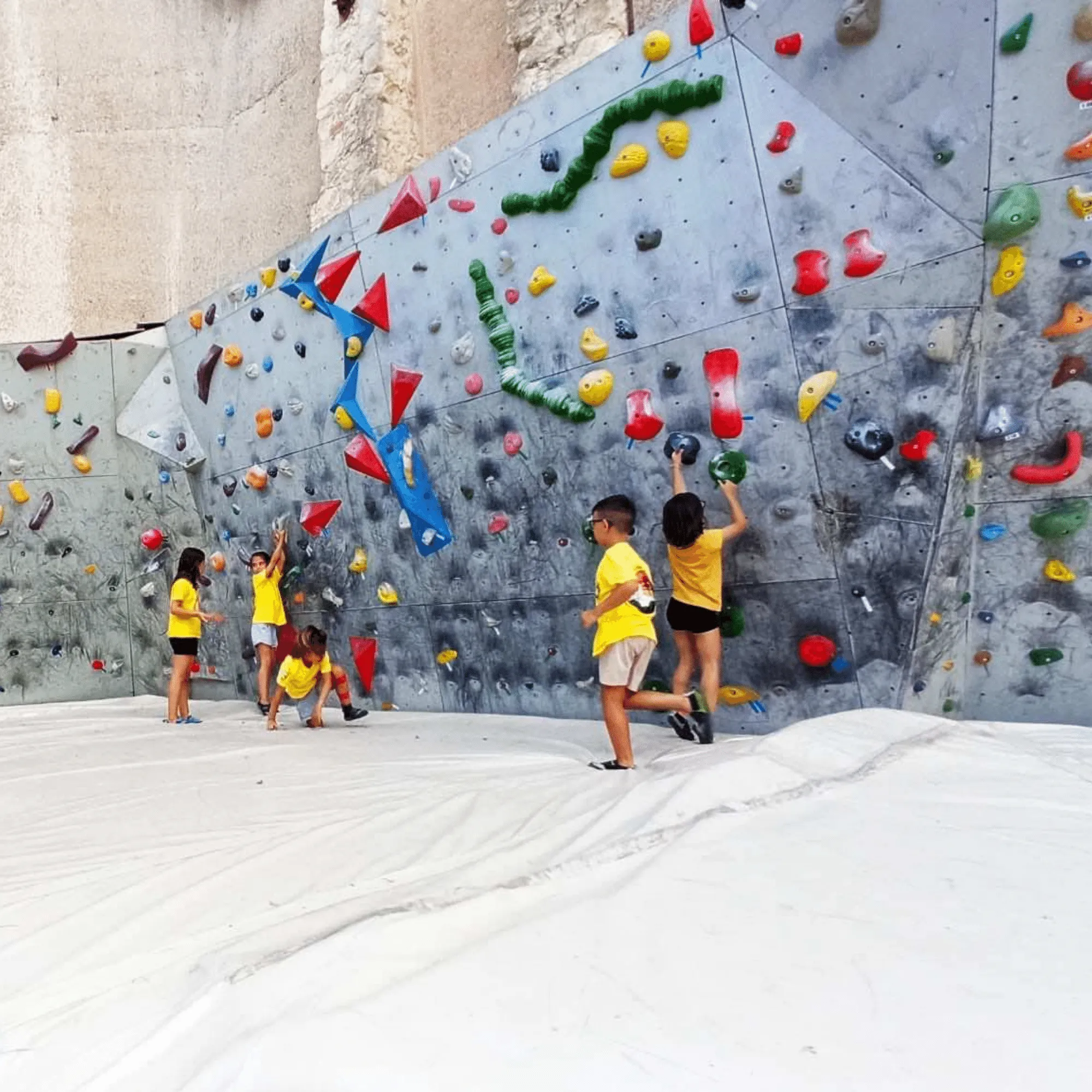 Bambini con le magliette gialle arrampicano sull’area boulder