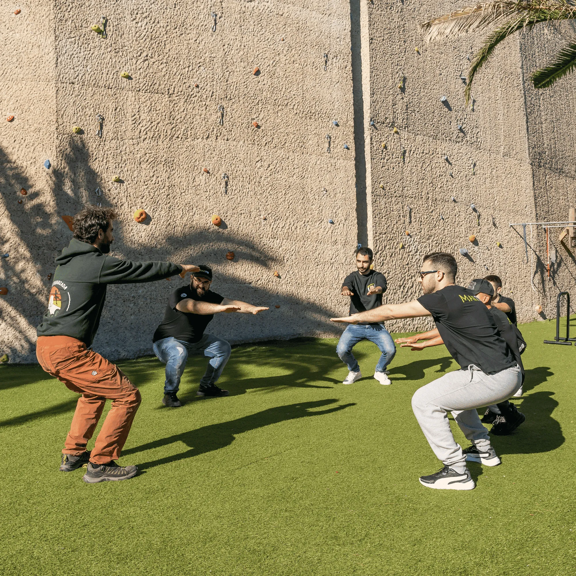 Un gruppo fa squat sul prato, ai piedi delle mura